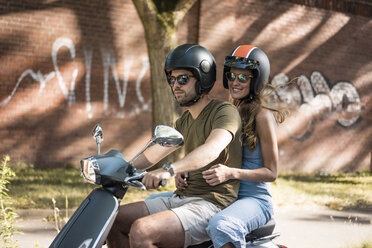 Glückliches Paar fährt Motorroller im Sommer - JOSF02555