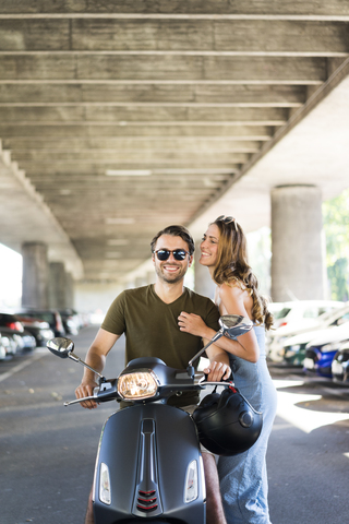 Glückliches Paar mit Motorroller an der Unterführung, lizenzfreies Stockfoto