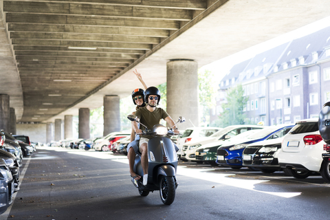 Glückliches Paar fährt Motorroller bei Unterführung, lizenzfreies Stockfoto