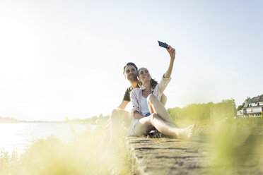 Glückliches Paar am Flussufer im Sommer, das ein Selfie macht - JOSF02569