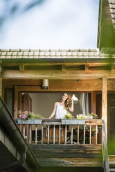 Portrait of smiling woman standing on balcony - JOSF02591