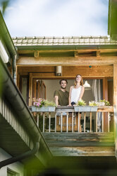 Smiling couple standing on balcony at home - JOSF02592