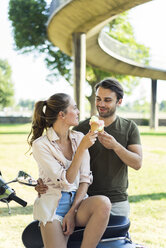 Smiling couple with motor scooter in summer eating ice cream - JOSF02596