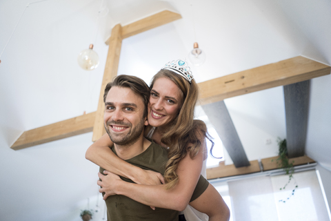 Porträt eines glücklichen Paares zu Hause mit einer Frau, die eine Tiara trägt, lizenzfreies Stockfoto