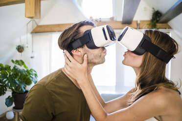 Couple wearing VR glasses kissing at home - JOSF02635