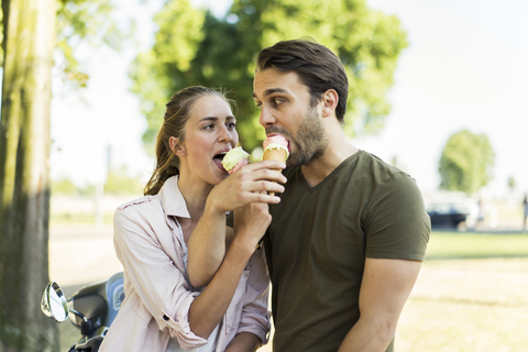 Couple with motor scooter in summer sharing ice cream stock photo