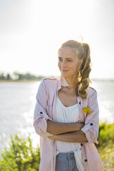 Portrait of smiling woman standing at the riverside in summer - JOSF02670