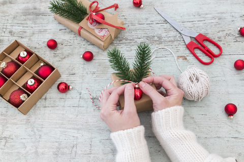 Frauenhände legen Dekoration auf Weihnachtsgeschenk, lizenzfreies Stockfoto