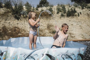 Bruder und seine kleine Schwester haben Spaß zusammen im Pool im Garten - KMKF00448