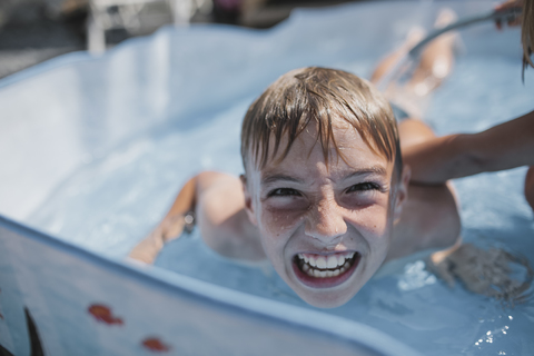 Porträt eines Jungen, der mit seiner Schwester im Pool spielt und lustige Gesichter zieht, lizenzfreies Stockfoto