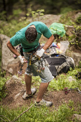 Italienischer Kletterer beim Befestigen von Kletterausrüstung (Freunde und Nüsse) an seinem Klettergurt, während er sich auf das Klettern einer schweren Rissroute vorbereitet. Esigo, Italien. - AURF03260