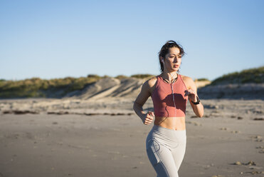 Junge Frau beim Laufen als Teil eines Workouts am frühen Morgen am Strand - AURF03269