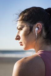 Young woman with earbuds working out during an early morning on the beach - AURF03270