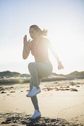 Junge Frau trainiert am frühen Morgen am Strand - AURF03272