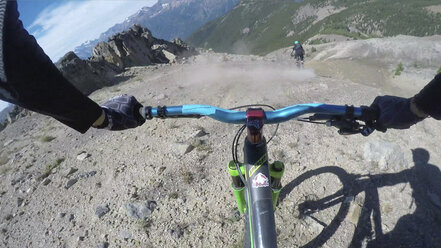 POV vorbei an den Händen eines Mountainbikers beim Abstieg vom Bergkamm - AURF03281