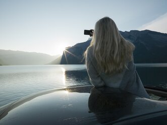Woman takes pic from car, mountain lake - AURF03323