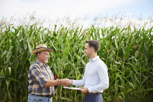 Farmer and businessman shaking hands at the cornfield - ABIF00949