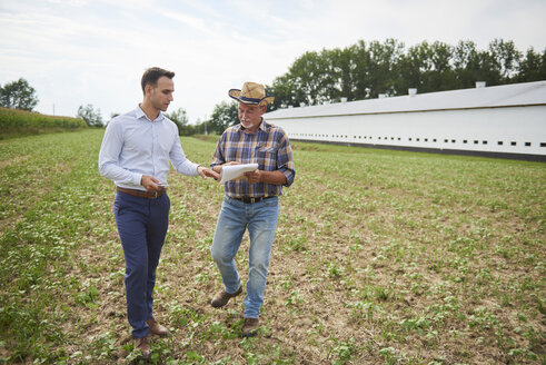 Landwirt und Geschäftsmann besprechen die Daten des Klemmbretts auf dem Feld - ABIF00950