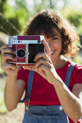 Lächelnde Frau beim Fotografieren mit Sofortbildkamera - KKAF01560