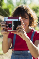 Smiling woman taking picture with instant camera - KKAF01560
