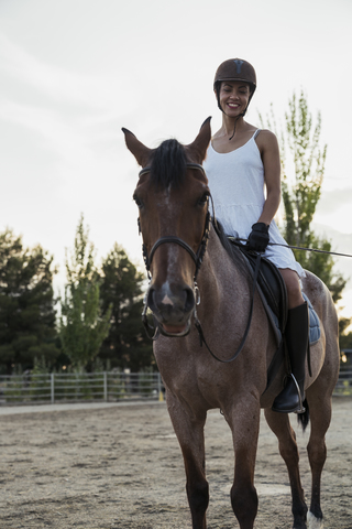 Lächelnde Frau auf einem Pferd sitzend, lizenzfreies Stockfoto