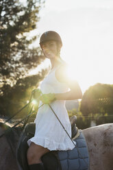 Portrait of smiling woman riding on horse at backlight - KKAF01583
