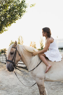 Barefoot woman sitting bareback on horse - KKAF01602