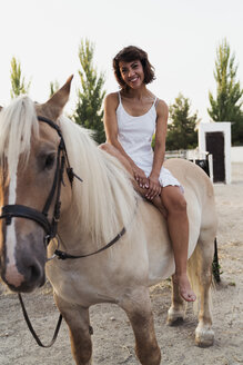Portrait of happy woman sitting bareback on horse - KKAF01604