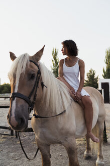 Barfüßige Frau sitzt barfuß auf einem Pferd - KKAF01605