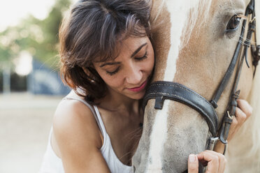 Woman cuddling riding horse - KKAF01612