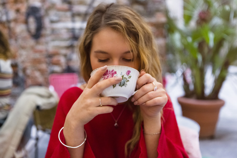 Porträt einer jungen Frau, die in einem Straßencafé eine Tasse Tee trinkt, lizenzfreies Stockfoto