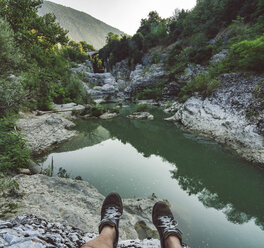Italy, Marche, Fossombrone, Marmitte dei Giganti canyon, Metauro river, hiker sitting on riverside, shoes - LOMF00745