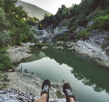 Italien, Marken, Fossombrone, Marmitte dei Giganti Schlucht, Metauro Fluss, Wanderer sitzt am Flussufer, Schuhe - LOMF00745