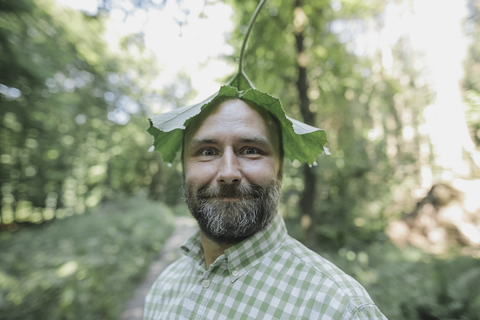 Porträt eines lächelnden Mannes mit Blatt auf dem Kopf, lizenzfreies Stockfoto