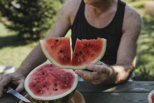 Die Hand eines älteren Mannes hält eine Scheibe Wassermelone - KMKF00480