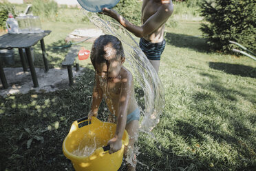 Bruder und Schwester spielen mit Wasser im Garten - KMKF00505