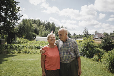 Glückliches Seniorenpaar im Garten stehend - KMKF00515