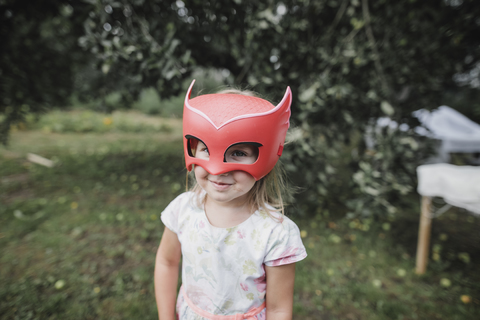 Porträt eines lächelnden kleinen Mädchens mit roter Maske, lizenzfreies Stockfoto