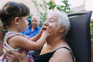 Grandmother and granddaughter playing together on terrace - GEMF02375