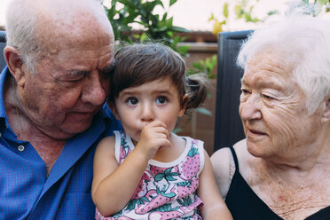 Großeltern betrachten ein kleines Mädchen beim Daumenlutschen - GEMF02382