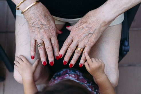 Hand eines kleinen Mädchens, das auf die Hand einer älteren Frau mit Ringen und rot lackierten Nägeln zeigt - GEMF02385