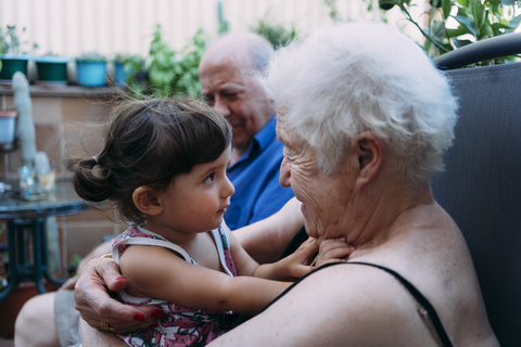 Großeltern und Enkelin verbringen Zeit miteinander auf der Terrasse, lizenzfreies Stockfoto