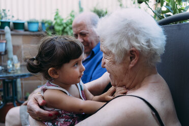 Großeltern und Enkelin verbringen Zeit miteinander auf der Terrasse - GEMF02387