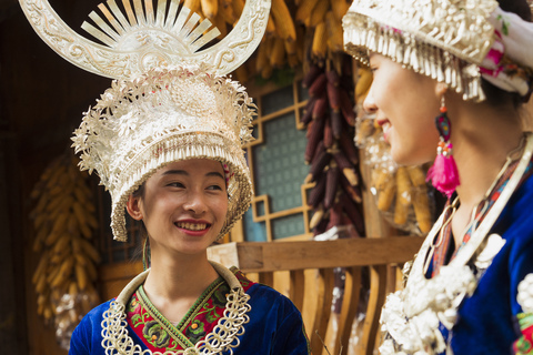 China, Guizhou, two smiling young Miao women wearing traditional dresses and headdresses stock photo