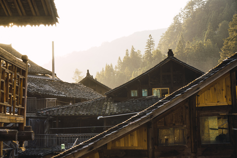 China, Guizhou, Häuser einer Miao-Siedlung im Gegenlicht, lizenzfreies Stockfoto