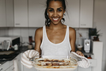 Porträt einer lächelnden jungen Frau mit einer Kasserolle in der Küche - LHPF00018