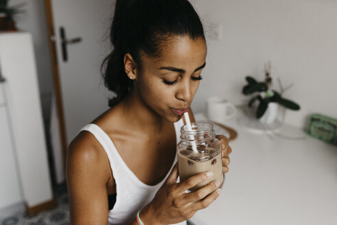 Junge Frau trinkt ein Glas Eiskaffee in der Küche - LHPF00021
