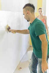 Man painting wall at new home while his girl friend watching him - FBAF00032