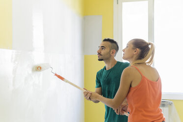 Ehepaar streicht gemeinsam eine Wand im neuen Haus - FBAF00033
