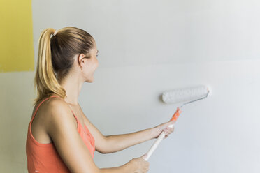 Junge Frau streicht Wand in neuem Haus - FBAF00035